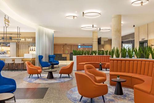 a lobby with orange and blue chairs and tables at Wyndham Wroclaw Old Town in Wrocław