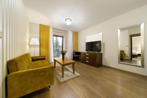 een woonkamer met een bank en een televisie bij Pilsner Apartments - U Borského parku in Pilsen