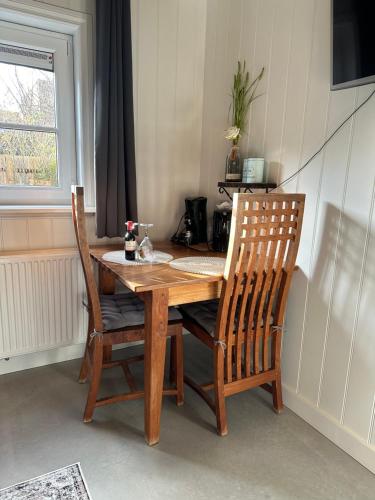 een houten tafel met twee stoelen en een tafel en een raam bij La Fattoria Bed&breakfast in Venhuizen