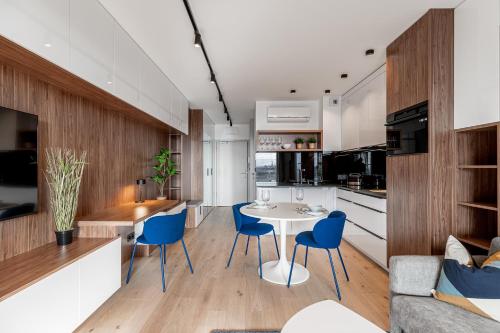 a kitchen and living room with a white table and blue chairs at Otyńska Point Apartamenty Prestige in Wrocław
