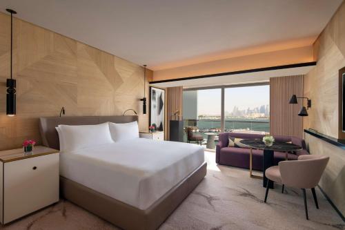 Rixos Gulf Hotel Doha في الدوحة: غرفة نوم مع سرير وغرفة معيشة