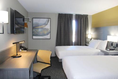 Habitación de hotel con 2 camas y escritorio en Days Inn by Wyndham Stony Plain, en Stony Plain