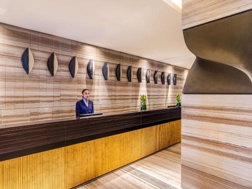 a man standing at a counter in a lobby at Rixos Gulf Hotel Doha in Doha