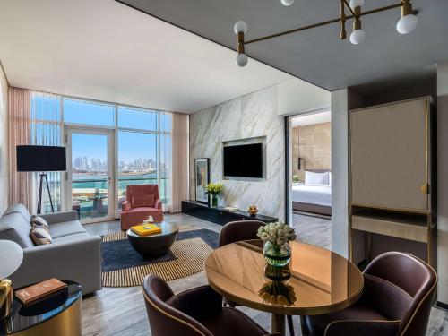 a living room with a couch and a room with a bed at Rixos Gulf Hotel Doha in Doha
