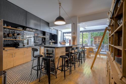 une cuisine avec des placards noirs et des tabourets de bar dans l'établissement Superbe appartement T5 proche du Palais et de la Croisette, à Cannes