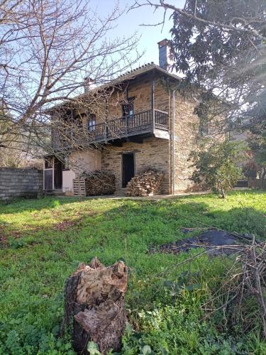 a stone house with a balcony on top of a yard at CASA DA RIBEIRA in Quiroga