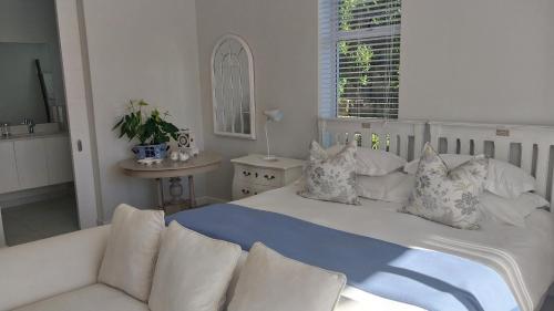 a white bed with pillows and a couch in a room at Knysna Private Estate Lagoon Apartment - Garden Apartment - Secure Estate in Knysna