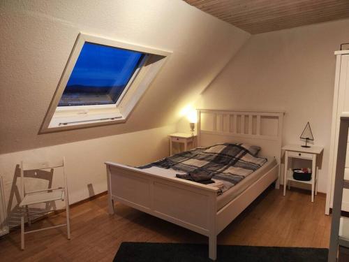 een slaapkamer met een bed met een raam en een stoel bij Spatzenbergzimmer 2 in Obersulm