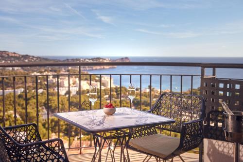 a table and chairs on a balcony with wine glasses at Hilton Mallorca Galatzo in Paguera
