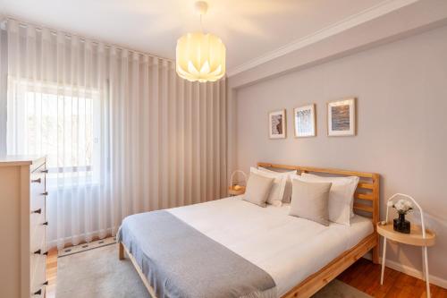 埃斯波森迪的住宿－Esposende Beach Apartment - Minho's Guest，一间卧室配有一张床和一个吊灯