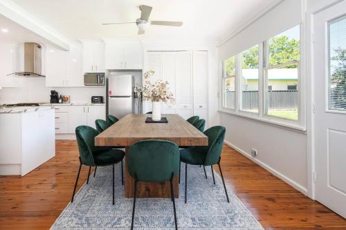 a kitchen and dining room with a wooden table and green chairs at Bancroft House on Scenic Mudgee Golf Course in Mudgee
