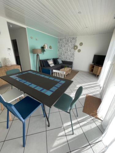 a living room with a table and chairs and a couch at Maison 6 personnes Soulac Climatisée Fibre in Soulac-sur-Mer