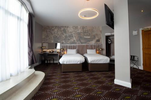 um quarto de hotel com duas camas e uma secretária em The Saxon Crown Wetherspoon em Corby