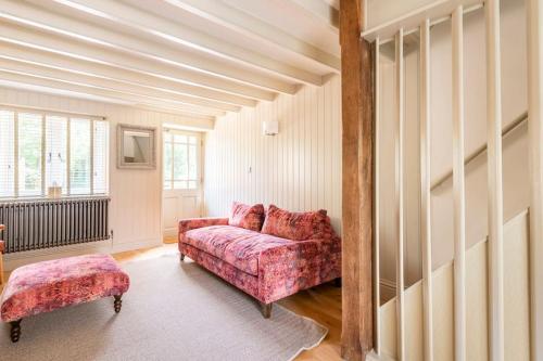 ein Wohnzimmer mit einem rosa Sofa und einem Stuhl in der Unterkunft Idilic Cottage The Sheaf in Blockley