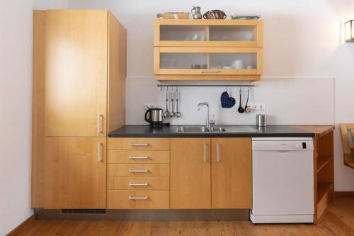 a kitchen with wooden cabinets and a white dishwasher at Appartementhotel am Weissensee in Weissensee