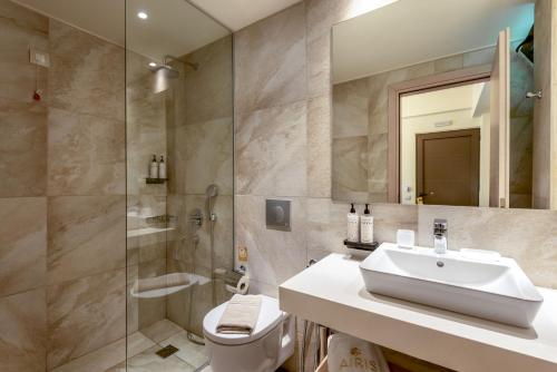 a bathroom with a sink and a shower and a toilet at Airis Boutique Hotel & Suites - For adults only in Kato Daratso