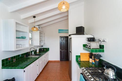 a kitchen with white cabinets and green counter tops at Hodges Bay House in Calibishie