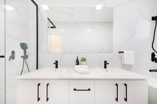 Baño blanco con 2 lavabos y espejo en 'Infinity's Edge' Darwin Luxury Waterfront Oasis, en Darwin