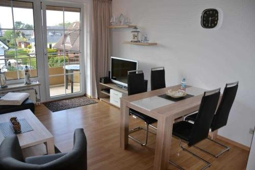 ein Wohnzimmer mit einem Tisch, Stühlen und einem TV in der Unterkunft (DKK11) Ferienwohnung Strandburg in Niendorf