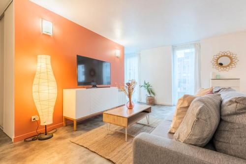 uma sala de estar com um sofá e uma televisão de ecrã plano em Spacious apartment w private parking in Old Lille em Lille