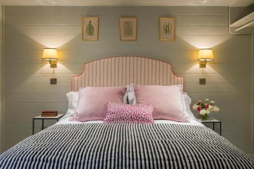een slaapkamer met een bed met roze en zwarte kussens bij The Outbuilding Appledore in Snargate