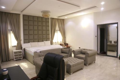 a bedroom with a bed and a couch and chairs at 1164 Residence Apartment in Abuja