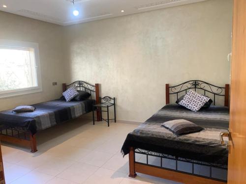 - une chambre avec 2 lits et une fenêtre dans l'établissement Maison à louer pour couple marié ou groupe fille, à Agadir