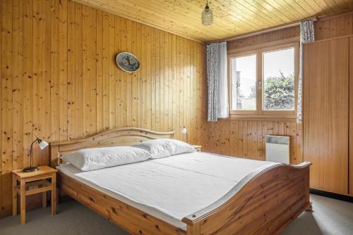 ein Schlafzimmer mit einem großen Bett an einer Holzwand in der Unterkunft Schwarzbueb in Bettmeralp