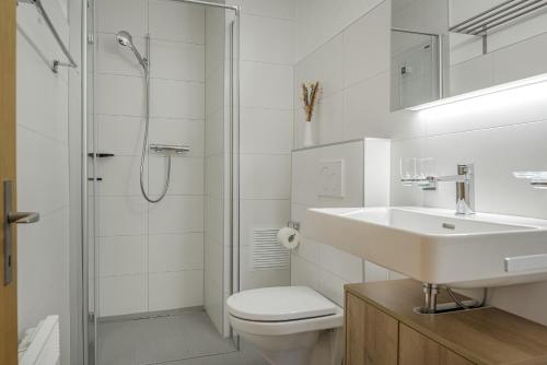 ein weißes Bad mit einem Waschbecken und einer Dusche in der Unterkunft Schwarzbueb in Bettmeralp