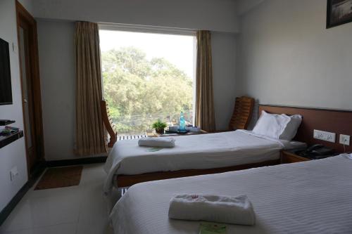 a hotel room with two beds and a window at Kingscross Residency in Chennai