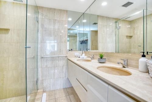 a bathroom with two sinks and a glass shower at Retro Main Beach Hidden Gem with Waterfront Views in Gold Coast