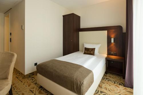 a bedroom with a large bed and a chair at Hotel Schopenhauer Hof in Frankfurt/Main