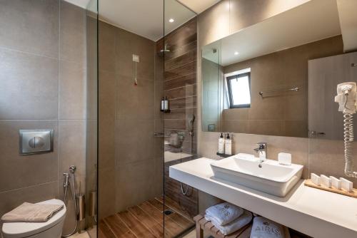 a bathroom with a sink and a toilet and a mirror at Airis Boutique Hotel & Suites - For adults only in Kato Daratso