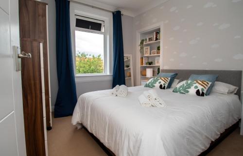 a bedroom with a bed with blue curtains and a window at Linburn Cottage Dunfermline near Edinburgh in Dunfermline