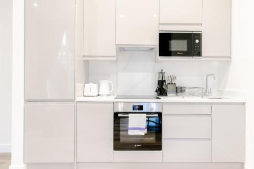 a white kitchen with a stove and a microwave at Stylish Apartments - Hyde Park in London
