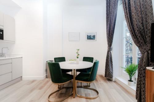 a dining room with a table and green chairs at Stylish Apartments - Hyde Park in London