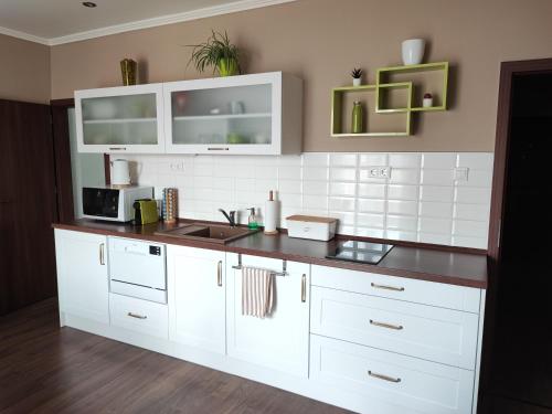a kitchen with white cabinets and a black counter top at Marianna Apartman Kaposvár in Kaposvár
