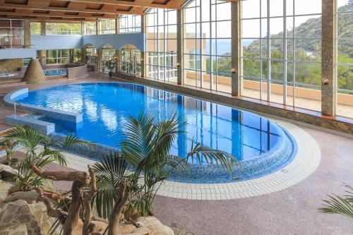 ein großer Pool in einem Gebäude mit Fenstern in der Unterkunft Zel Costa Brava in Tossa de Mar