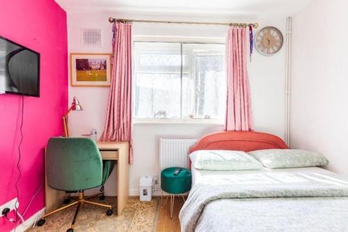Schlafzimmer mit rosa Wänden, einem Bett und einem Schreibtisch in der Unterkunft Inviting 2-Bed Apartment in Hounslow in Hounslow