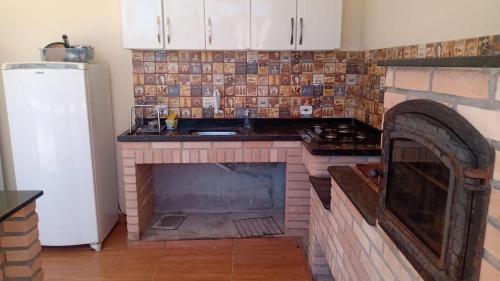 - une cuisine avec une cheminée au milieu dans l'établissement Chácara Nossa Senhora Aparecida, à Ribeirão Pires