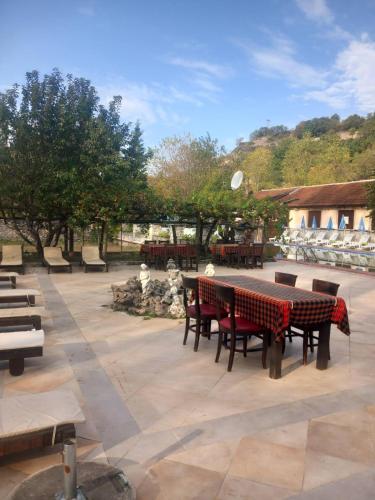 a patio with a table and benches and trees at Парк - Хотел Макензен in Melnik