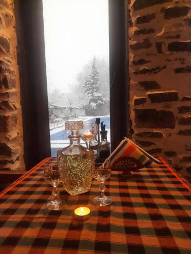 a table with glasses and a vase and a window at Парк - Хотел Макензен in Melnik