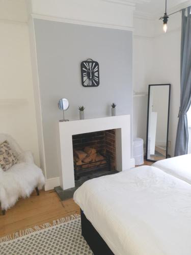 a white bedroom with a fireplace and a mirror at Mulberry House Excellent central location Courtyard garden 3 Bedrooms sleeps up to 6 Parking in Exeter