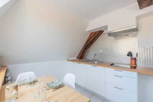 une cuisine avec une table en bois et des armoires blanches dans l'établissement Duplex next to Grand Place, à Lille