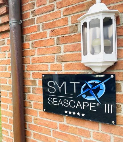 a sign on the side of a brick wall with a light at Sylt Seascape III in Tinnum