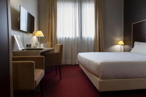 トリノにあるアート ホテル オリンピックのベッドとデスクが備わるホテルルームです。