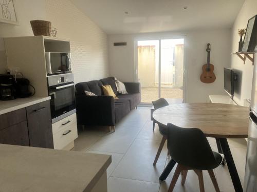eine Küche und ein Wohnzimmer mit einem Tisch und einem Sofa in der Unterkunft maison entre plage marais et forêt in Olonne-sur-Mer