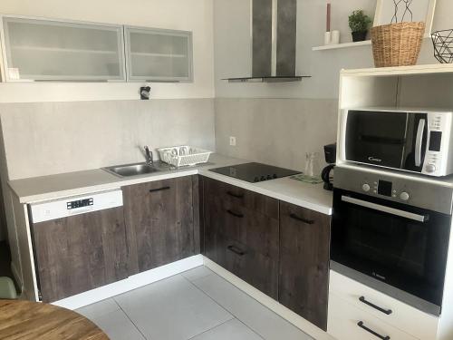 a small kitchen with a microwave and a sink at maison entre plage marais et forêt in Olonne-sur-Mer