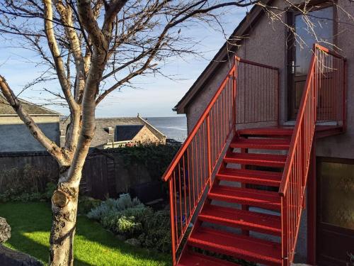 a red staircase leading up to a house at Top Floor Flat Ceol Na Mara (Music of the Sea) in Rosemarkie
