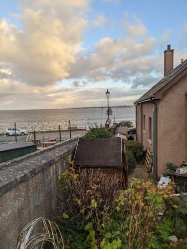 a building next to a beach with the ocean at Top Floor Flat Ceol Na Mara (Music of the Sea) in Rosemarkie